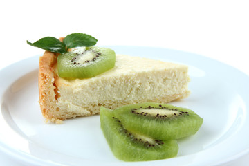 Slice of cheesecake with kiwi fruit on plate, isolated on white