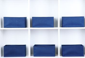 Blue textile boxes in white shelves