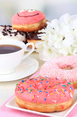 Sweet donuts with cup of tea on table on light background