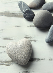 Grey stone in shape of heart, on color wooden background