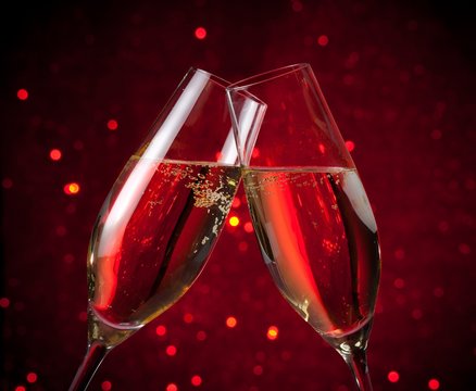 a pair of champagne flutes on red dark light bokeh background