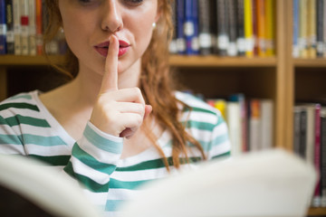 Redhead student asking for silence holding a book