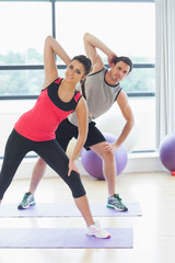 Fototapeta na wymiar Two people doing power fitness exercise at yoga class