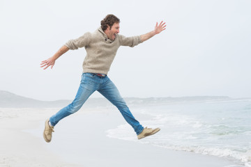 Obraz premium Side view of a casual man jumping at beach