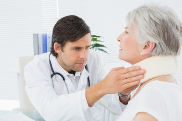 Obraz na płótnie Canvas Male doctor examining a senior patient's neck