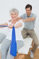 Male therapist assisting senior woman with exercises