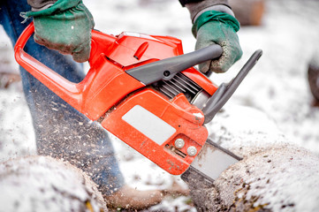 Hands using a chainsaw and cutting wood and trees