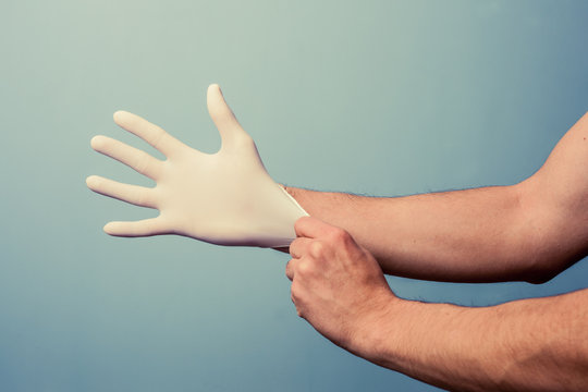 Health professional putting on surgical gloves