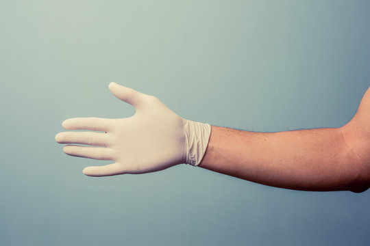 Hand wearing latex glove offering handshake