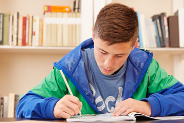 Naklejka premium Male teenager concentrated doing homework