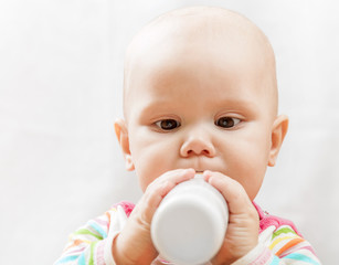 Little Caucasian baby with bottle of milk