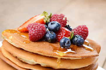 Pancakes with berries and honey closeup