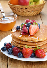 Pancakes with berries and honey closeup