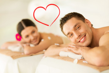 Obraz na płótnie Canvas smiling couple lying on massage table in spa salon