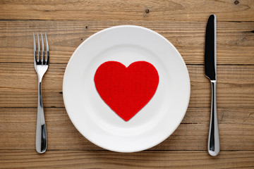 Red heart on plate on wooden background