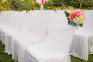 Empty white chairs in outdoor wedding