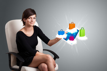 woman holding modern tablet with colorful shopping bags on cloud