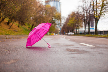Pink children's umbrella on the wet asphalt outdoors