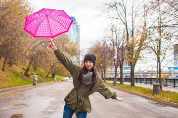 Young woman walking with umbrella in autumn rainy day
