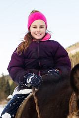 Little girl riding horse in winter