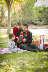 Naklejka na ściany i meble Mixed Race Family Enjoying Christmas Gifts in the Park Together