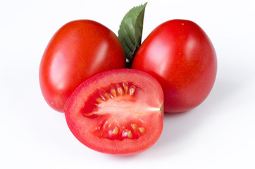 two red ripe plum tomatoes and their cut part inside lying on a white table Close-up on full frame isolated on white background - obrazy, fototapety, plakaty