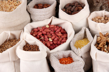 Different kinds of beans in sacks on wooden background
