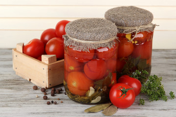 Tasty canned and fresh tomatoes on wooden table
