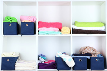 Blue textile boxes with towels and clothes in white shelves