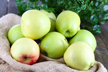 Juicy apples on sackcloth on wooden table