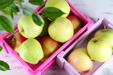 Juicy apples in boxes on wooden table