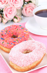 Sweet donuts with cup of tea on table close-up