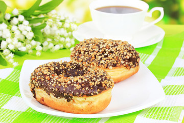 Sweet donuts with cup of tea on table on bright background