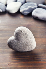 Fototapeta na wymiar Szary kamień w kształcie serca, na tle drewniane
