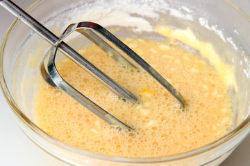 Cooking, whipping eggs with electric whisk in bowl, close up