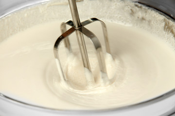 Cooking, whipping eggs with electric whisk in bowl, close up