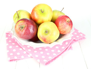 Juicy apples on plate on white wooden table