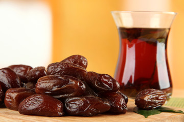 Dried dates with cup of tea on table on bright background