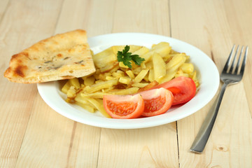 Fried potatoes on plate on wooden table close-up