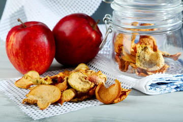 Dried apples in glass jar, on color wooden background