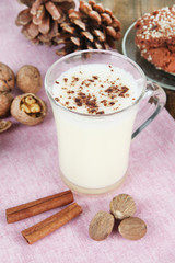 Cup of eggnog with cinnamon and nuts on table close up