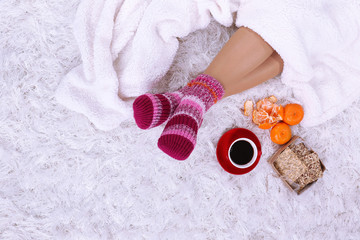 Composition with warm plaid, cup of hot drink and female legs,