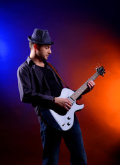 Obraz premium Young musician playing guitar on dark color background