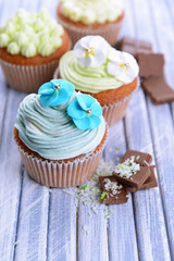 Tasty cupcakes with butter cream, on color wooden background