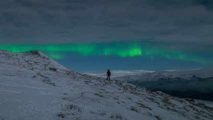Woman watching northern lights alone on mountain