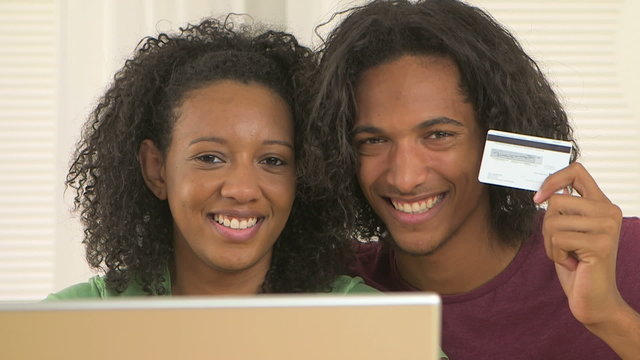 African couple using laptop and holding credit card