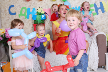 Five happy kids and facilitator with dogs of long balloons