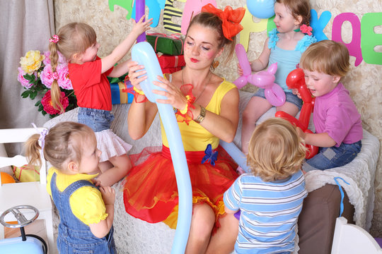 Five happy kids and facilitator make dogs of long balloons