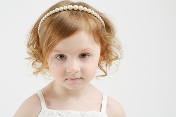 Little beautiful red hair girl in white dress on white