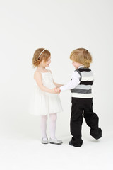 Little happy smiling girl and boy dance on white background.
